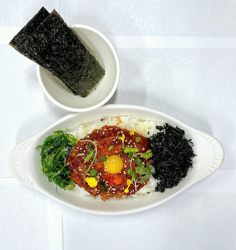 Korean seafood stew beside rice and sides.